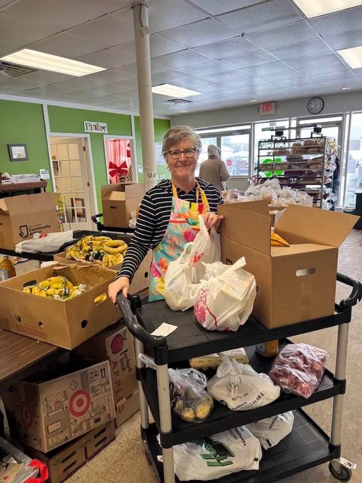 Volunteer with colorful apron preparing food bags at the Green Apple Pantry